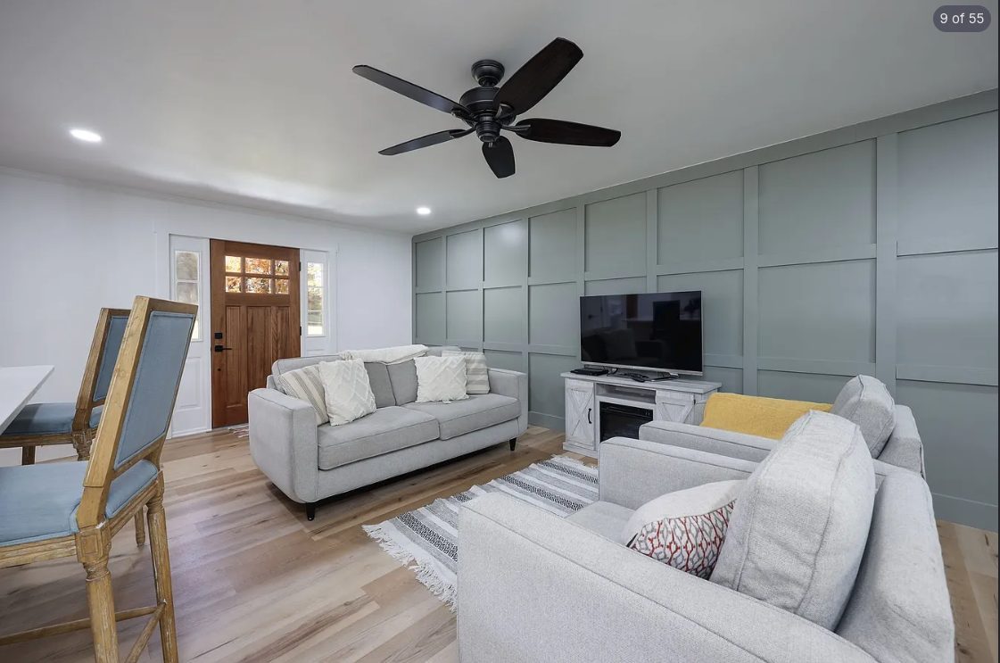 Living room with a sage green board-and-batten accent wall and light wood floors