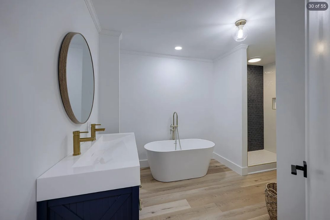 Bathroom with a navy vanity, white walls and a freestanding tub