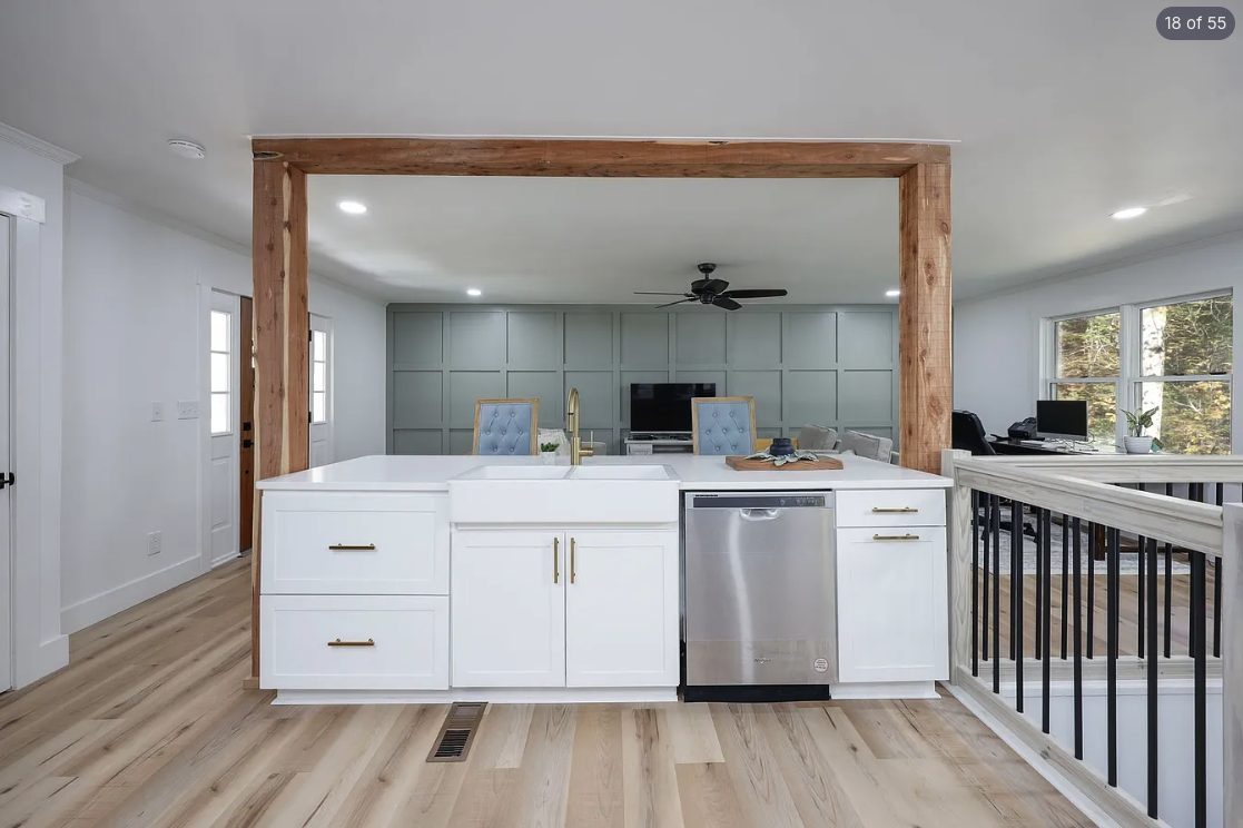 Open kitchen and living area with a sage accent wall and white cabinets